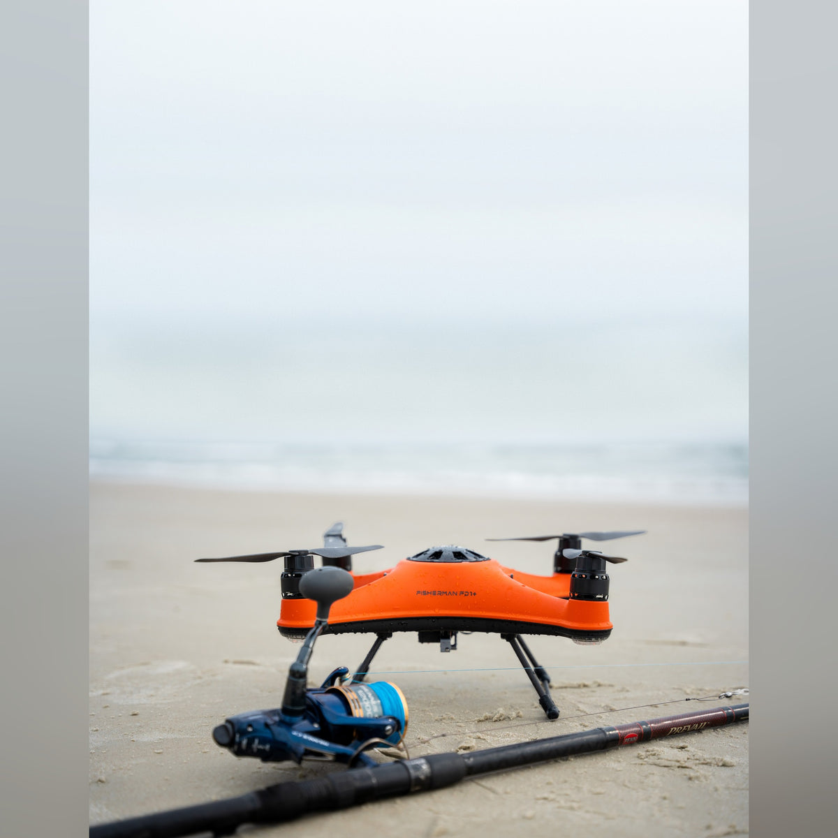 SwellPro Fisherman FD1+ on wet sand next to fishing rod
